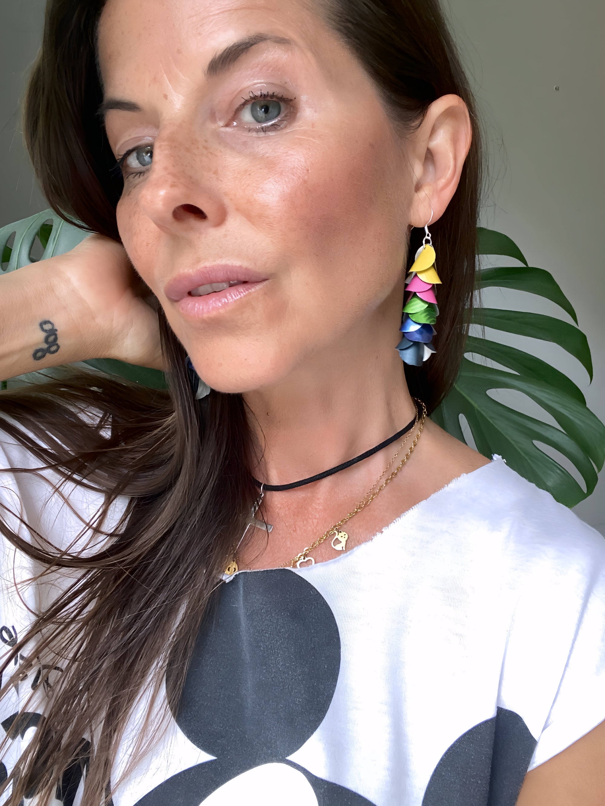 Woman wearing colorful earrings made from upcycled nespresso capsules with a neutral background