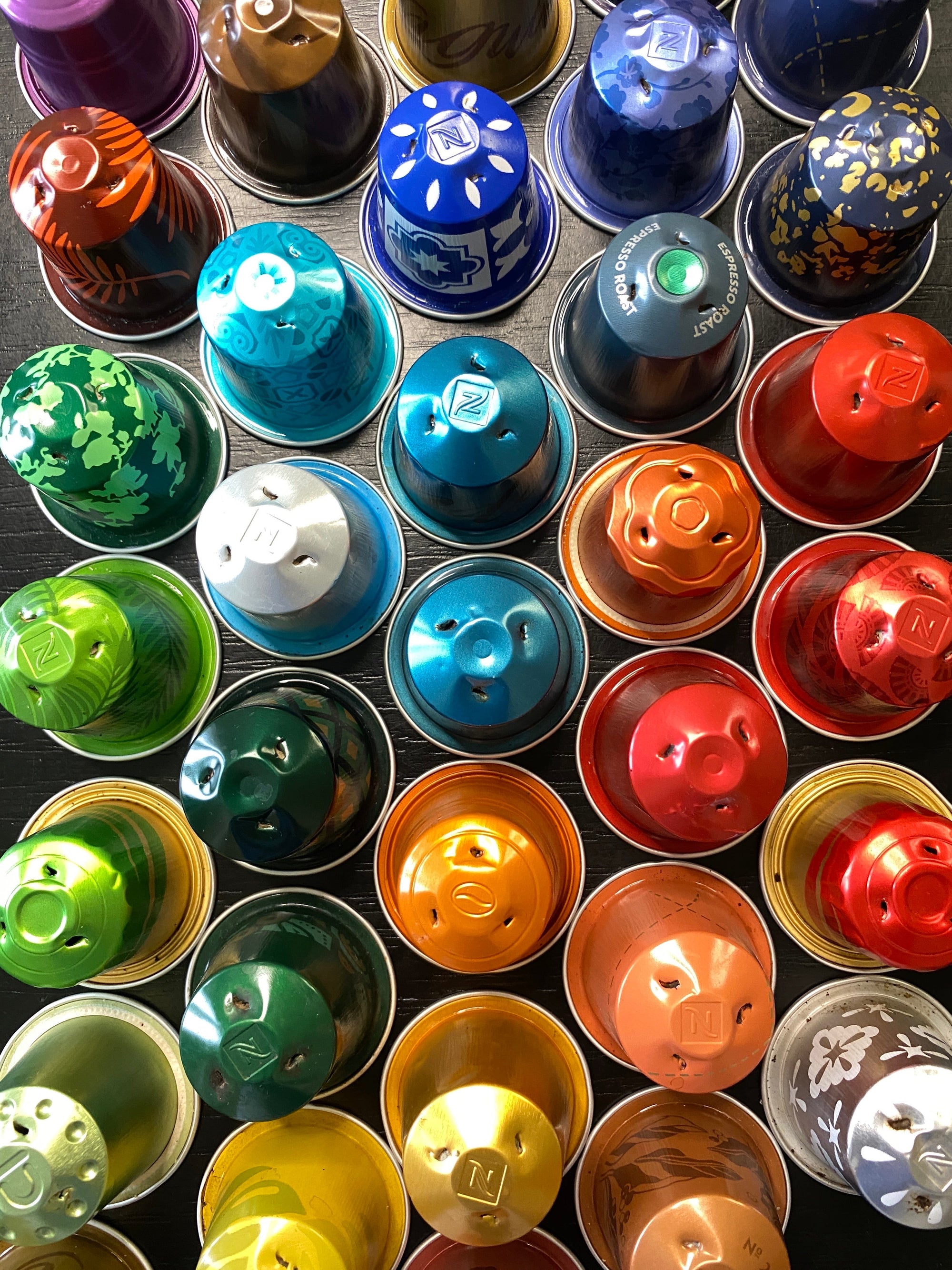 Assorted colorful coffee capsules arranged in a grid pattern.
