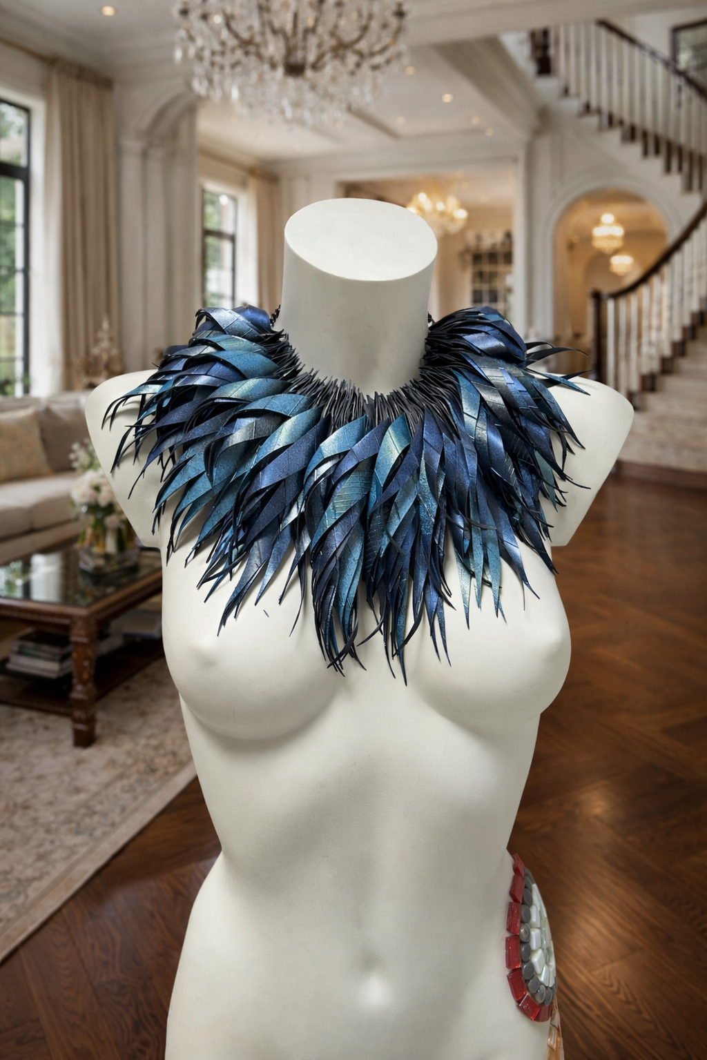 metallic bue coloured large, chunky curly tassel necklace made from upcycled bicycle inner tube on a white mannequin in  a luxurious home environment 