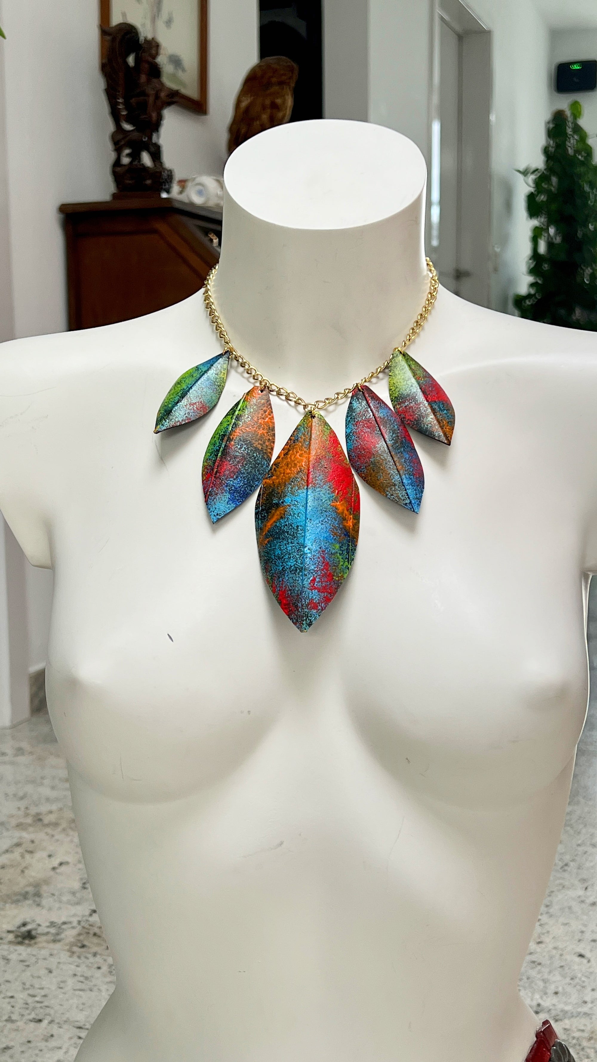 Mannequin wearing a colorful leaf-shaped necklace imade from upcycled bicycle inner tube rubber indoors.