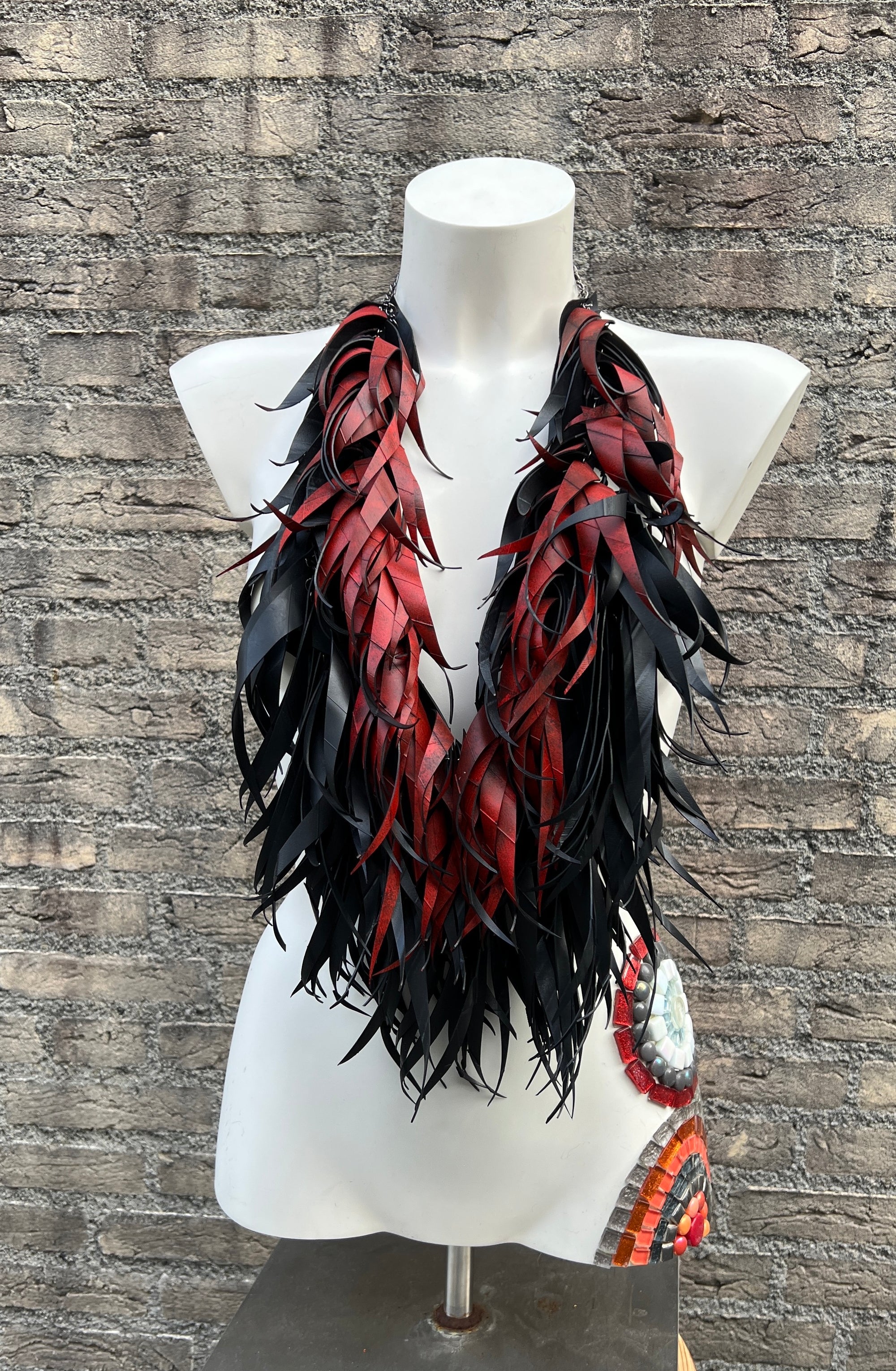 Mannequin wearing a red and black curly tassel necklace  made from upcycled bicycle inner tubes
