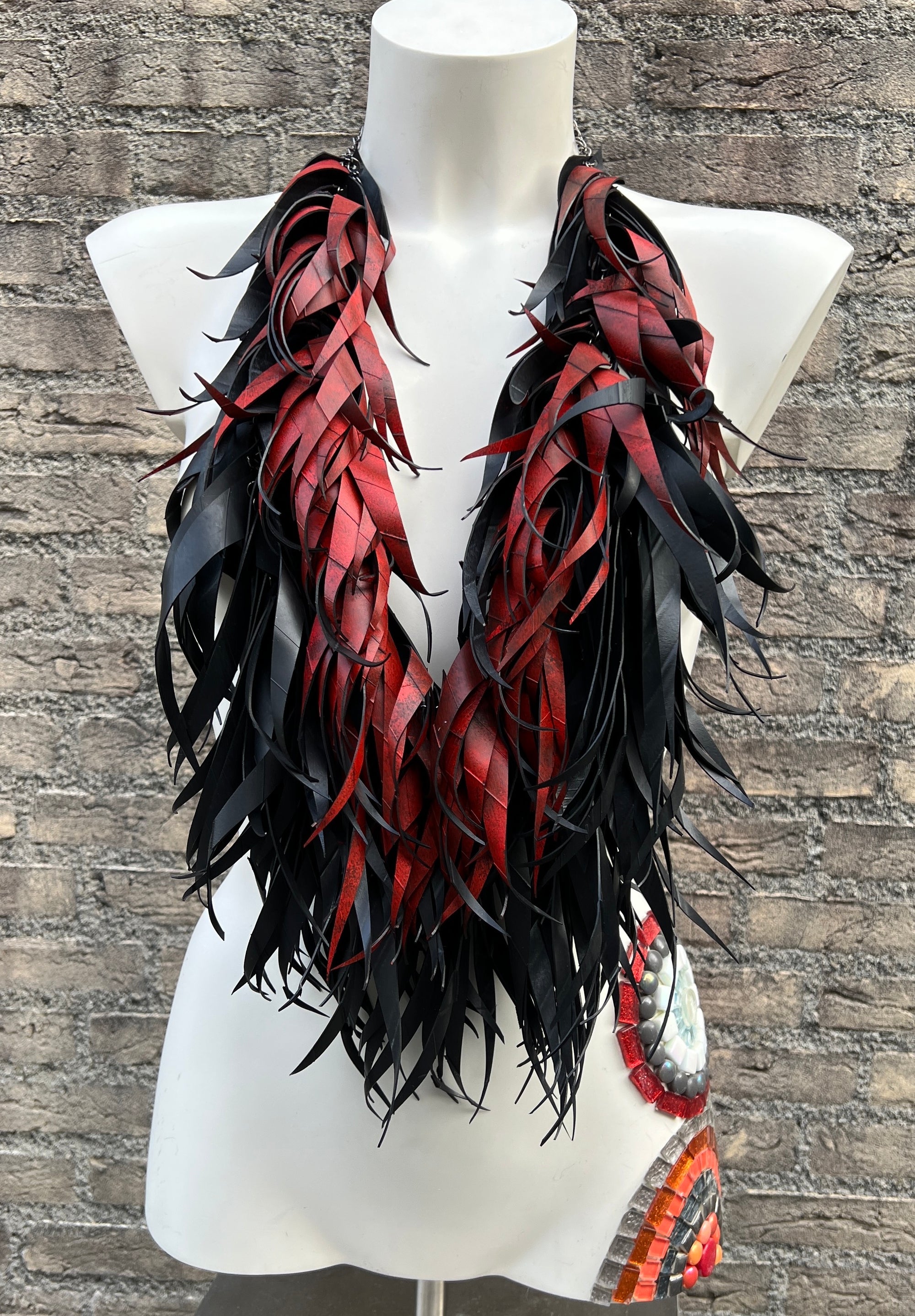 Mannequin wearing a vibrant red and black curly tassel necklace  made from upcycled bicycle inner tubes