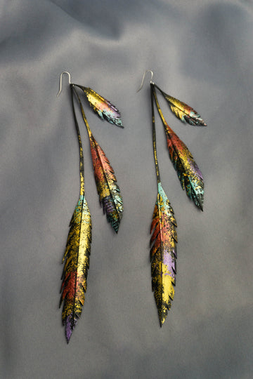 Metallic gold bronze painted recycled bicycle tyre rubber leaf shaped earrings, on a grey fabric background