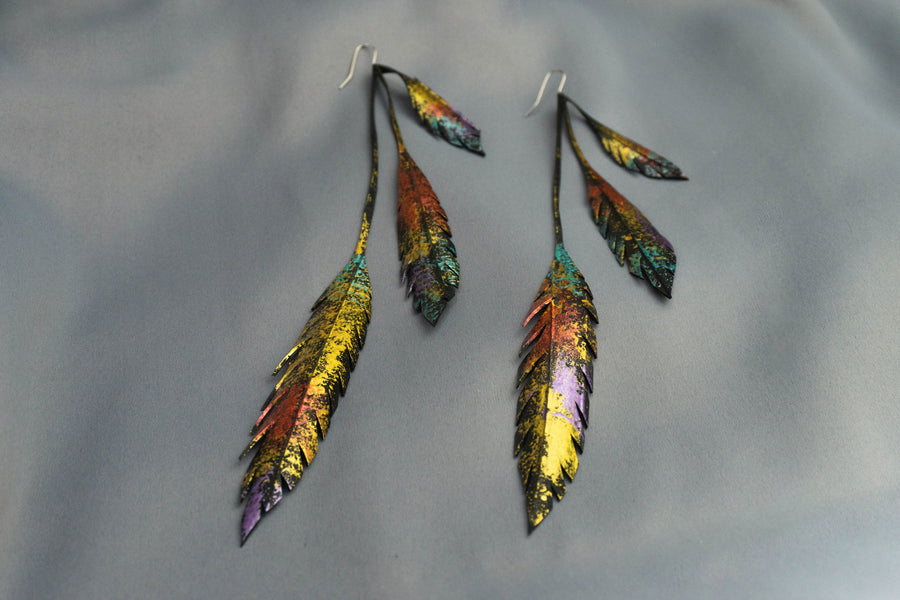 Metallic gold bronze painted recycled bicycle tyre rubber leaf shaped earrings, on a grey fabric background