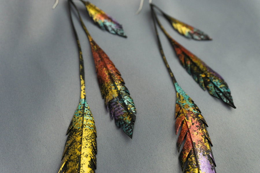 Metallic gold bronze painted recycled bicycle tyre rubber leaf shaped earrings, on a grey fabric background