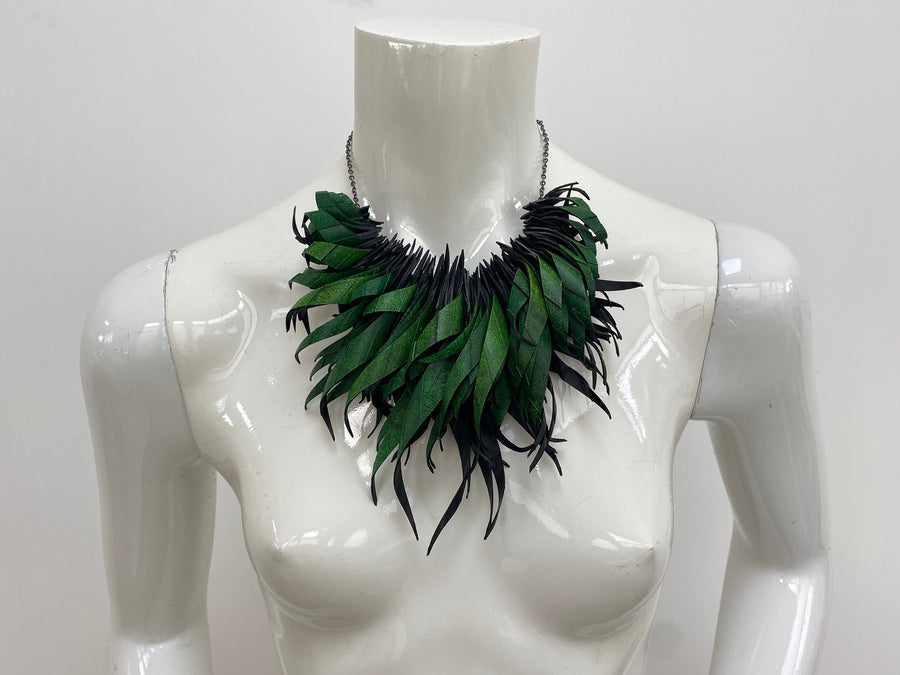 Green statement necklace, upcycled bicycle inner tube jewelry on a white mannequin