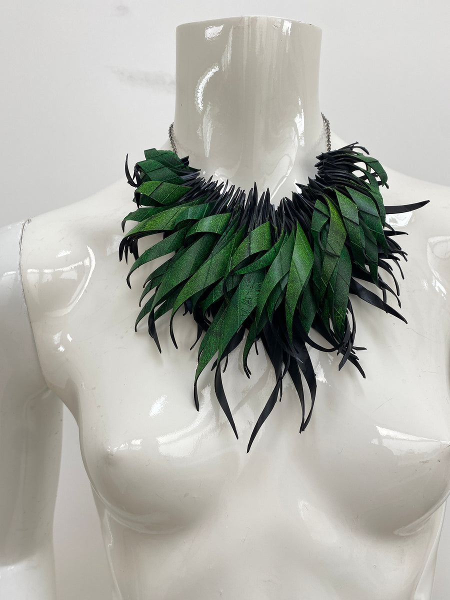 Green statement necklace, upcycled bicycle inner tube jewelry on a white mannequin