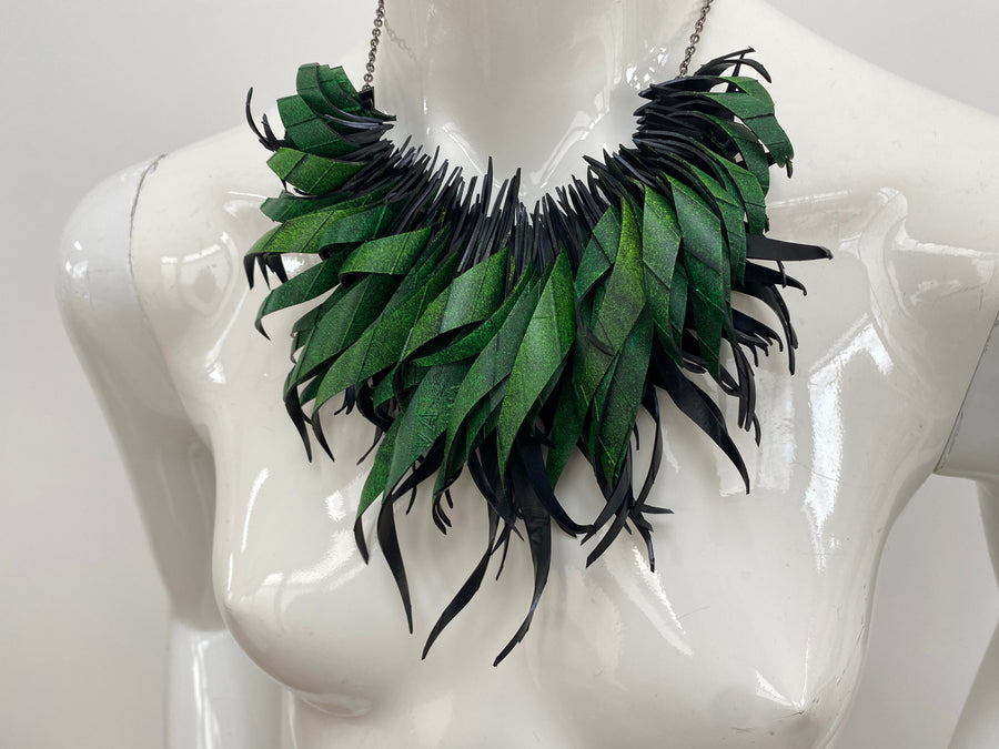 Green statement necklace, upcycled bicycle inner tube jewelry on a white mannequin