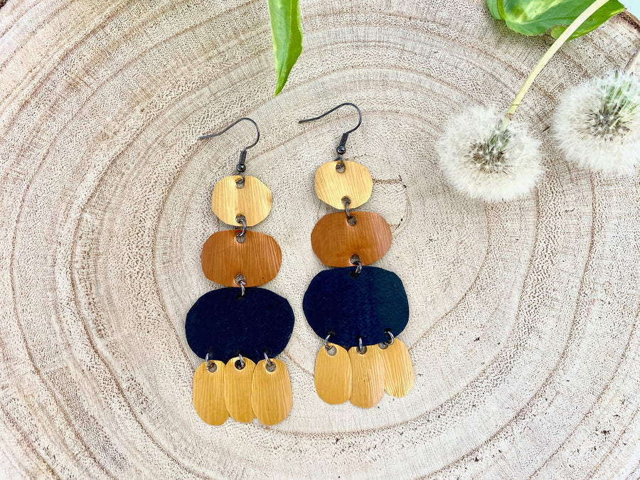 black gold bohemian upcycled bike tyrei nnertube and Nespresso capsules earrings on a wooden background and with dandelions