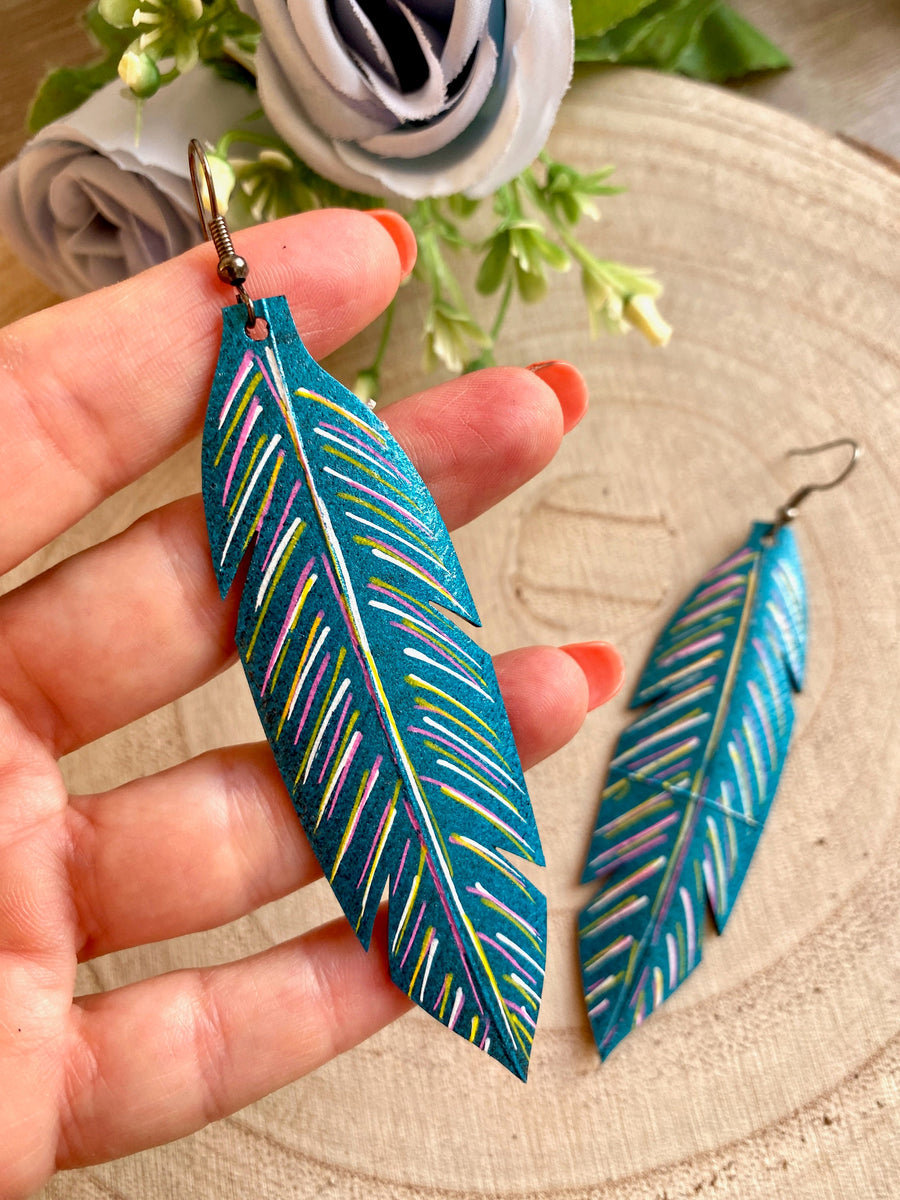 metallic aquamarine leaf shaped earrings made from upcycled bicycle tyre inner tubes on a wooden background