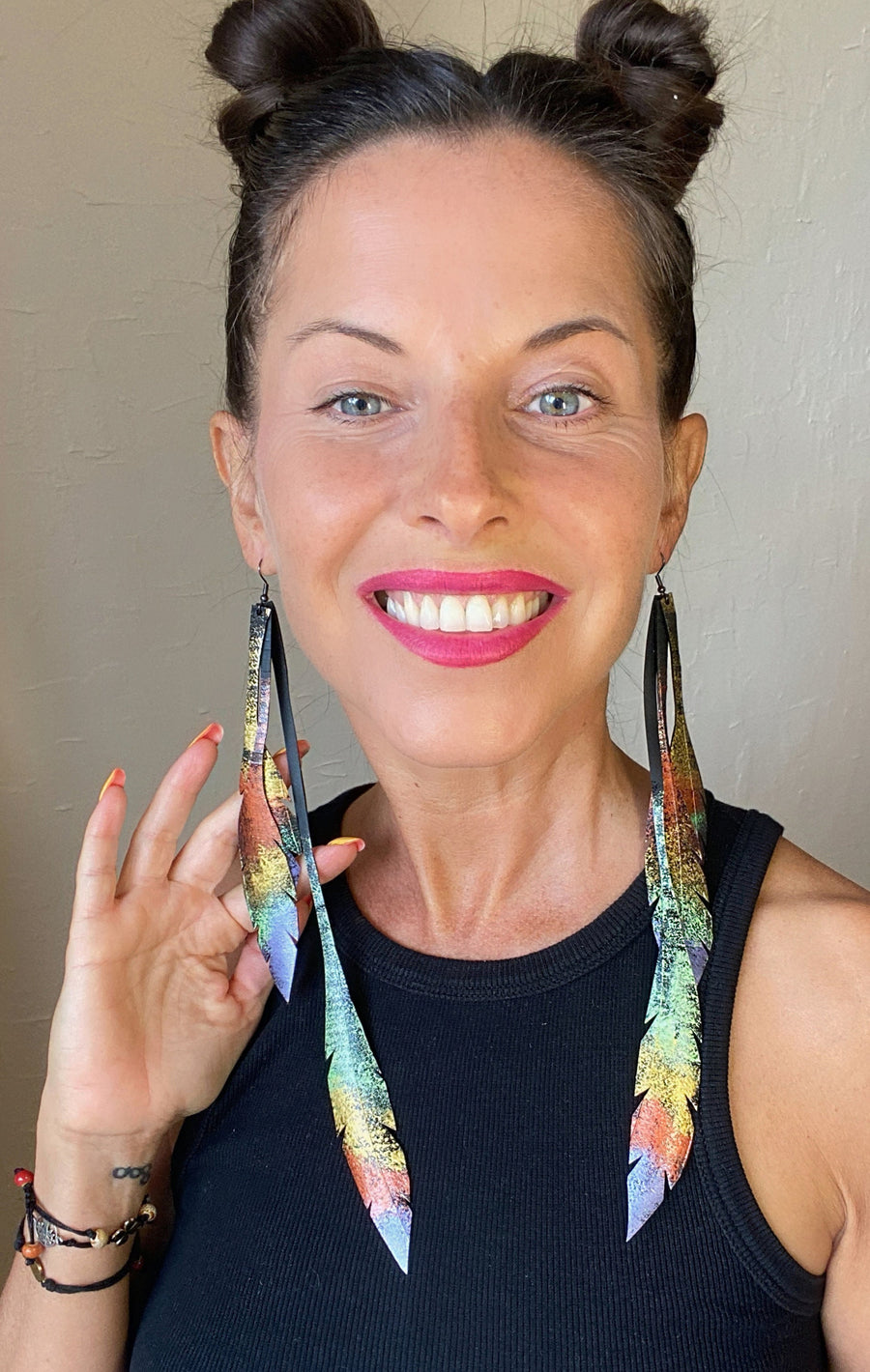 model wears metallic gold bronze painted recycled bicycle tyre rubber leaf shaped earrings, on a grey fabric background