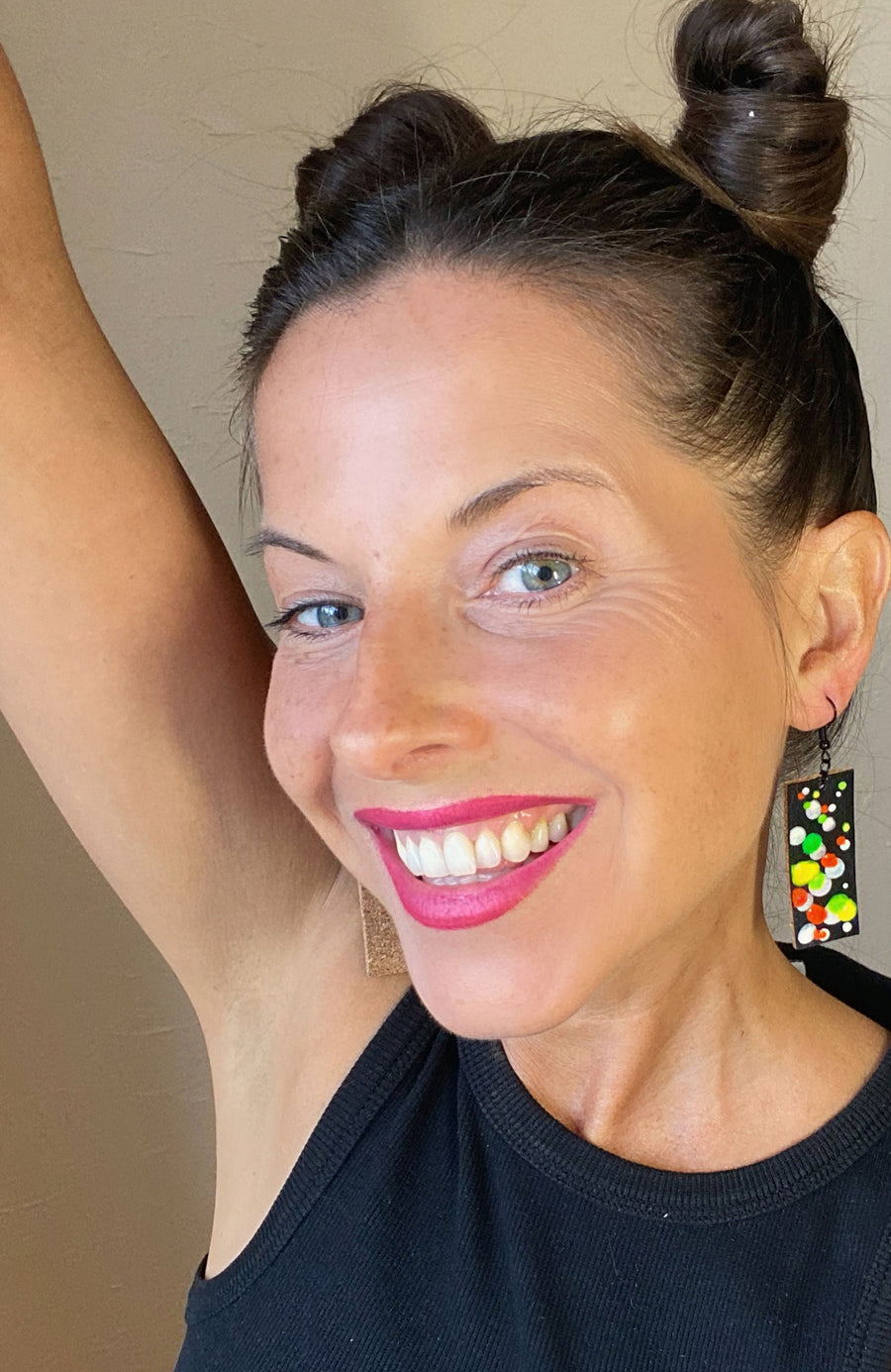 model wears squared-shaped earrings with black, white, orange, and yellow, green bubble design, made from upcycled bicycle inner tube