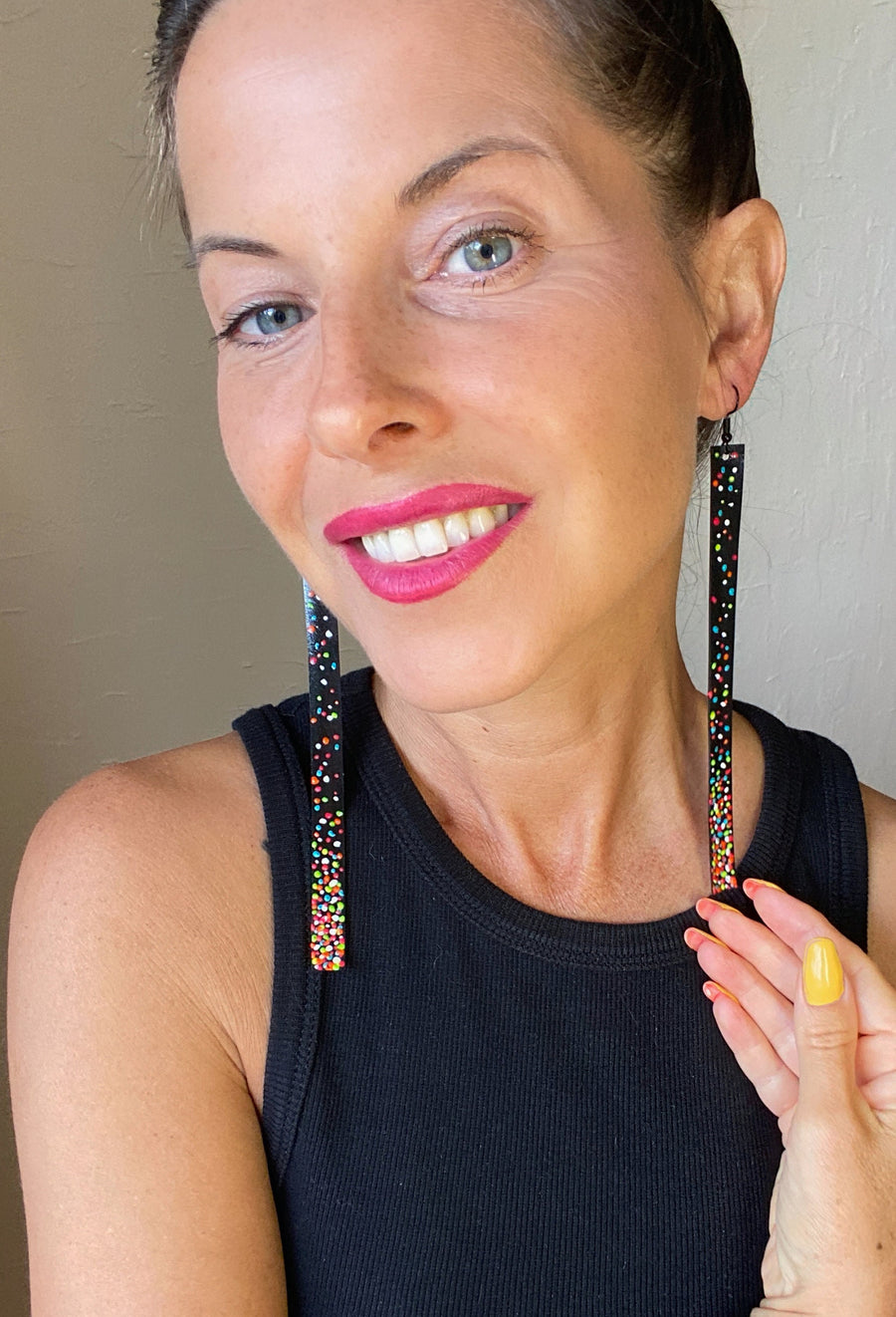 model wears black, upcycled bike inner tube earrings decorated with colourful polka dots