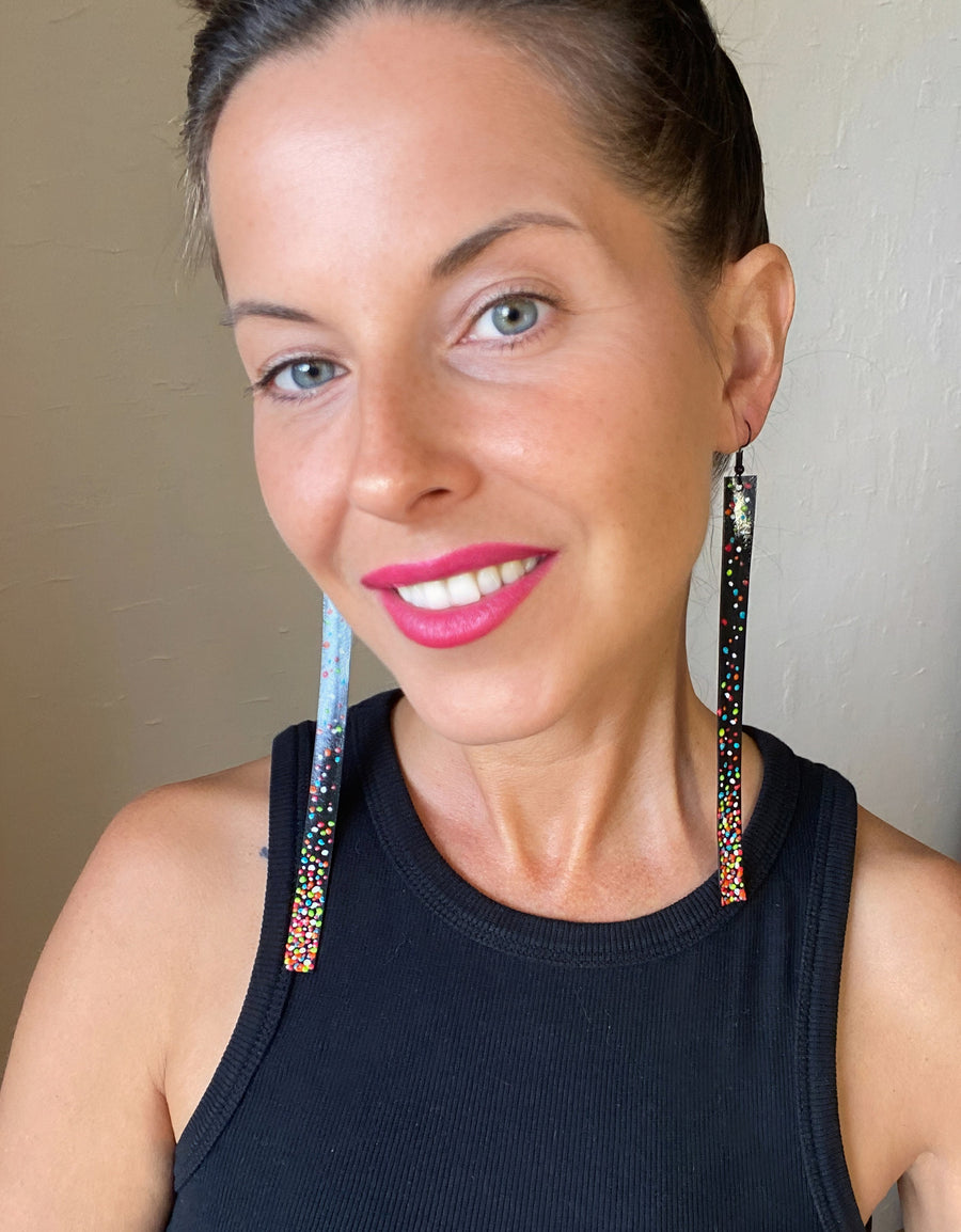 model wears black, upcycled bike inner tube earrings decorated with colourful polka dots