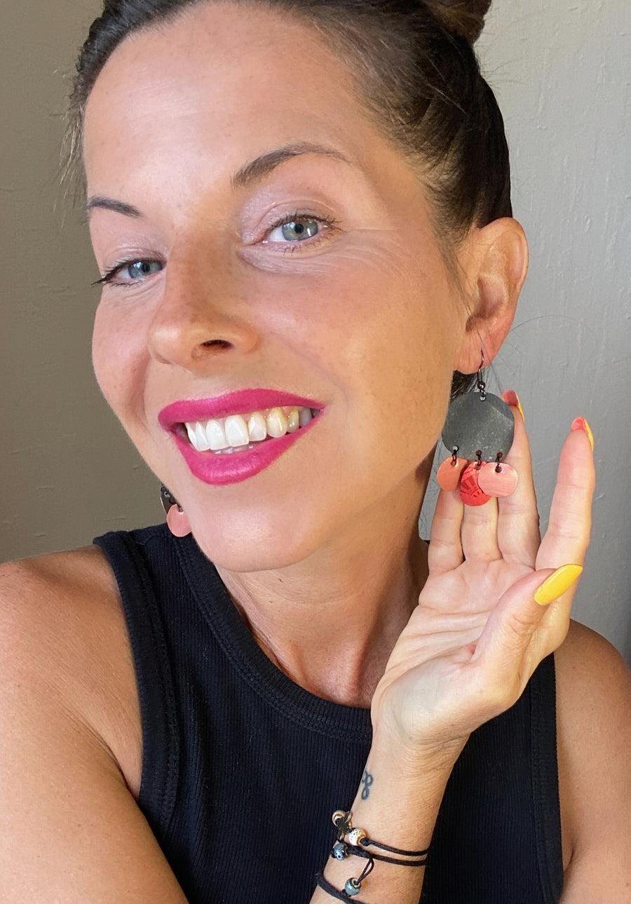 model wears black red peach coloured upcycled nespresso capsules and bike inner tube rubber earrings