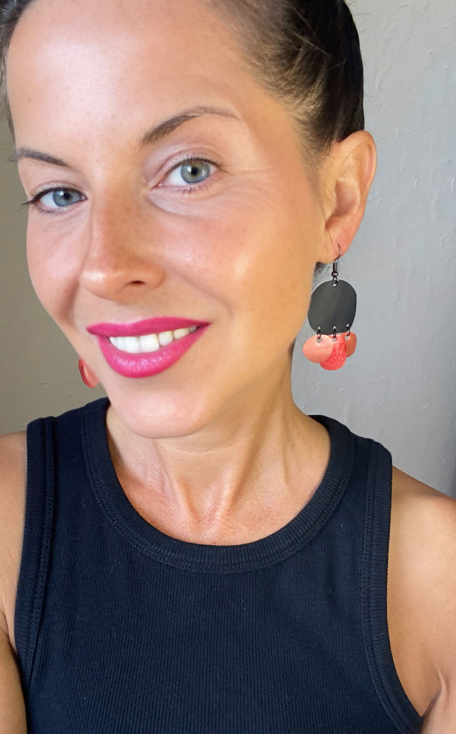 model wears black red peach coloured upcycled nespresso capsules and bike inner tube rubber earrings