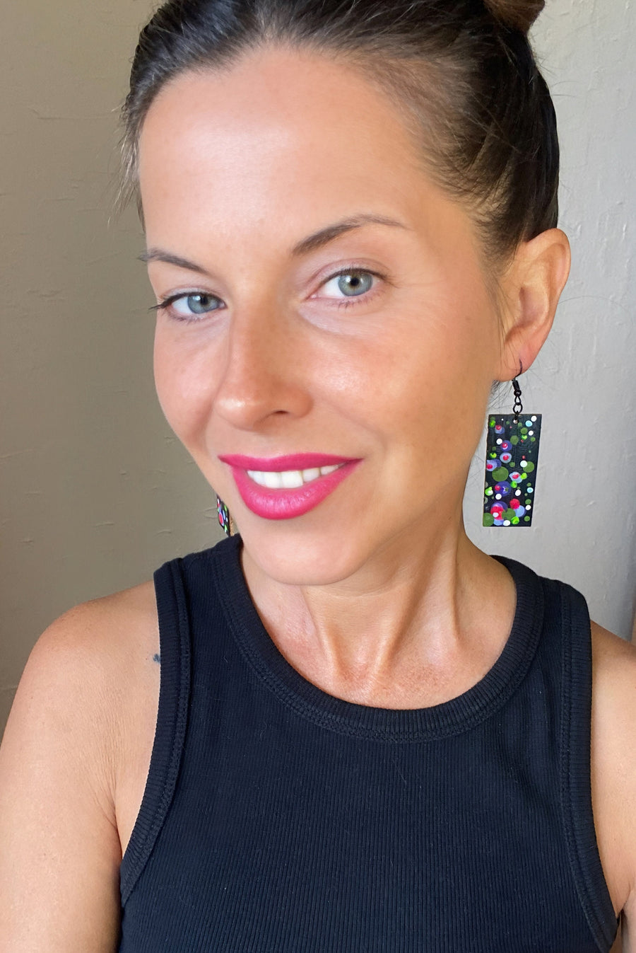 model wears squared-shaped earrings with black, white, green, and purple bubble design, made from upcycled material