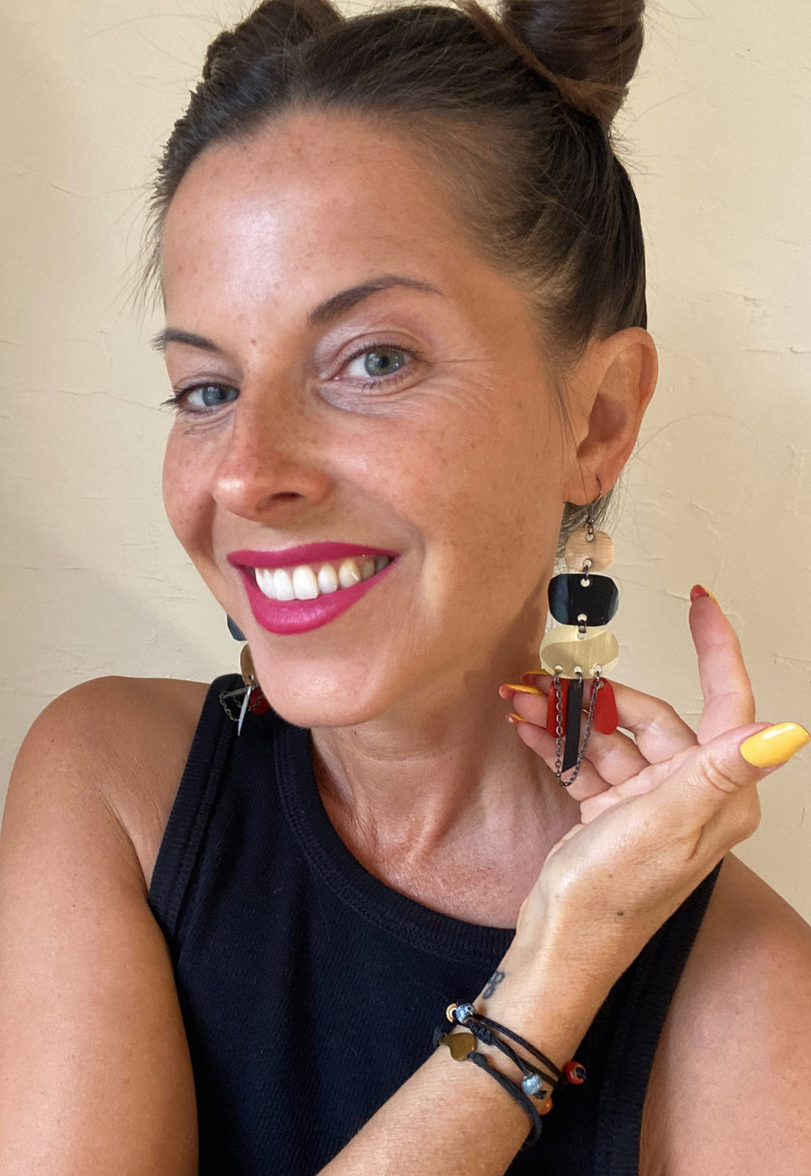 Laura Zabo wears oriental statement earrings made from upcycled Nespresso capsules, apricot, black, sand and red coloured jewelry