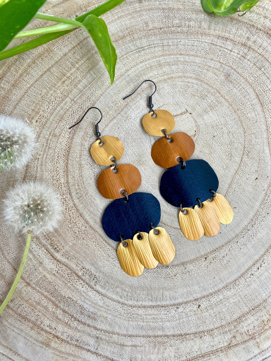 black gold bohemian upcycled bike tyrei nnertube and Nespresso capsules earrings on a wooden background and with dandelions