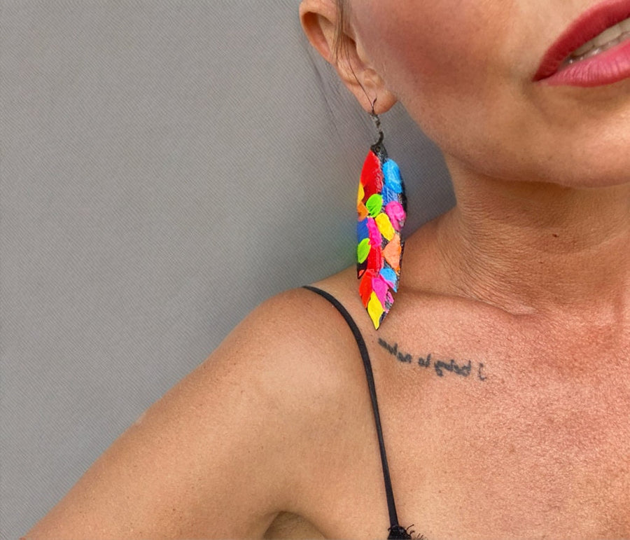 model wears pop art, abstract, neon coloured leaf shaped earrings made from upcycled bicycle inner tube rubber