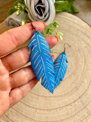 blue coloured leaf shaped, upcycled bicycle inner tube, rubber earrings on a wooden background