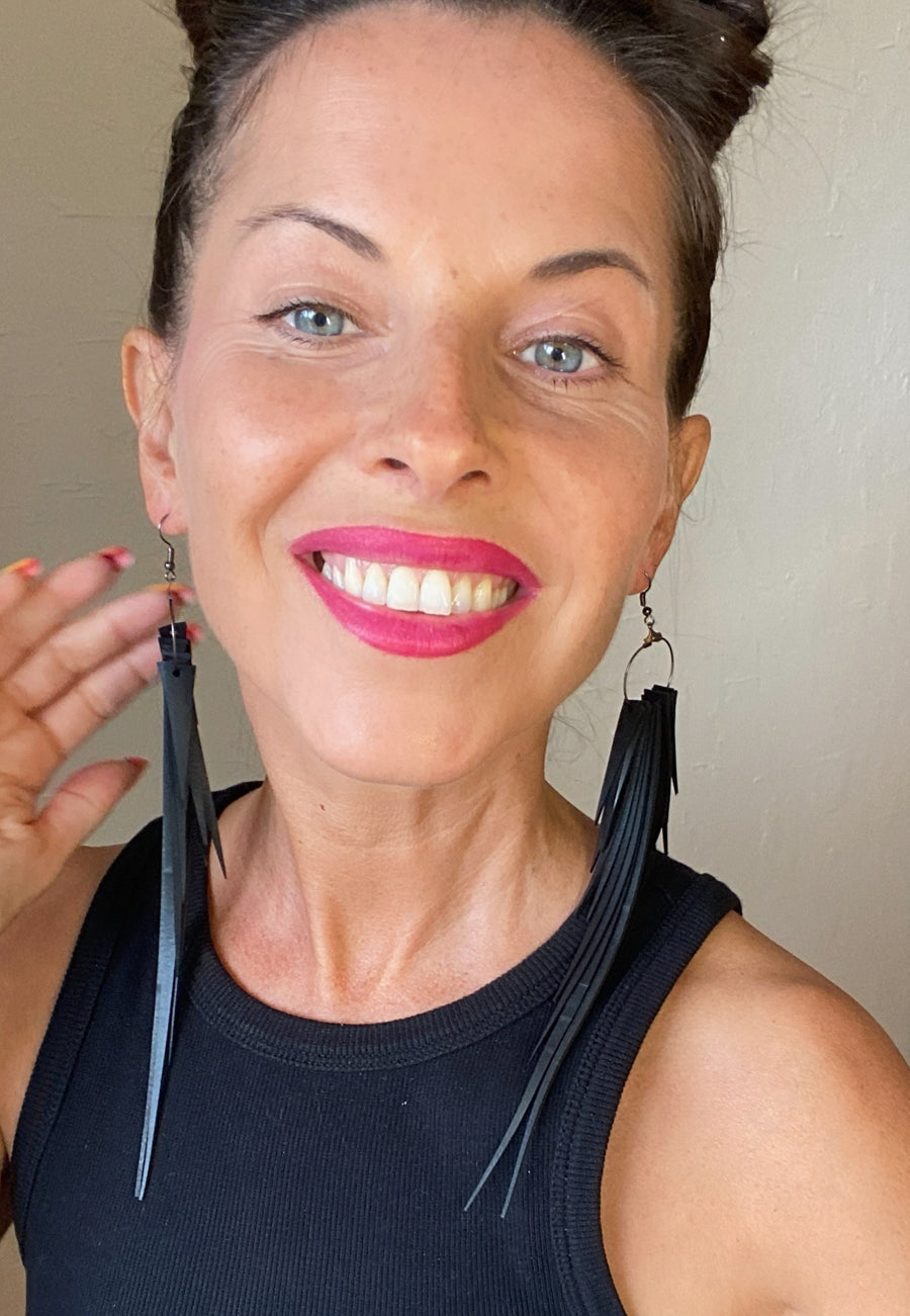 model wears black coloured upcycled bicycle inner tube tassel, fringe earrings, made from upcycled bicycle inner tube rubber