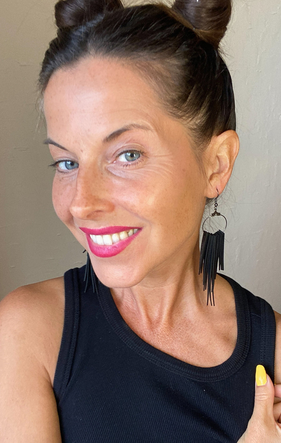 model wears long, black, upcycled bicycle inner tube tassel earrings made from bicycle tyre inner tubes on a wooden background