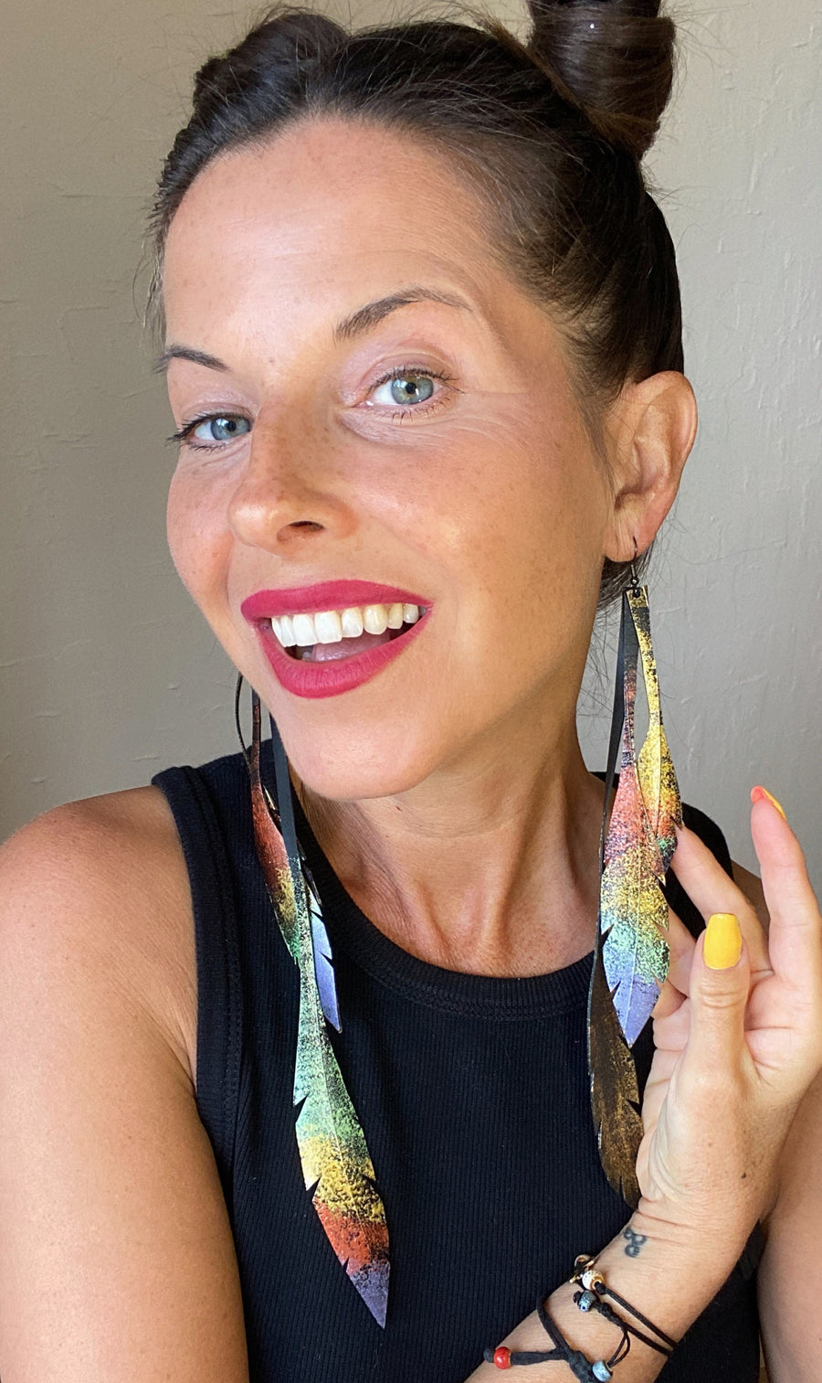 model wears metallic gold bronze painted recycled bicycle tyre rubber leaf shaped earrings, on a grey fabric background