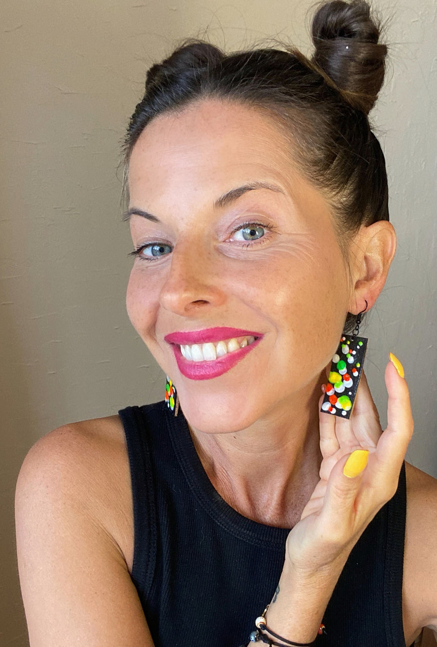 model wears squared-shaped earrings with black, white, orange, and yellow, green bubble design, made from upcycled bicycle inner tube