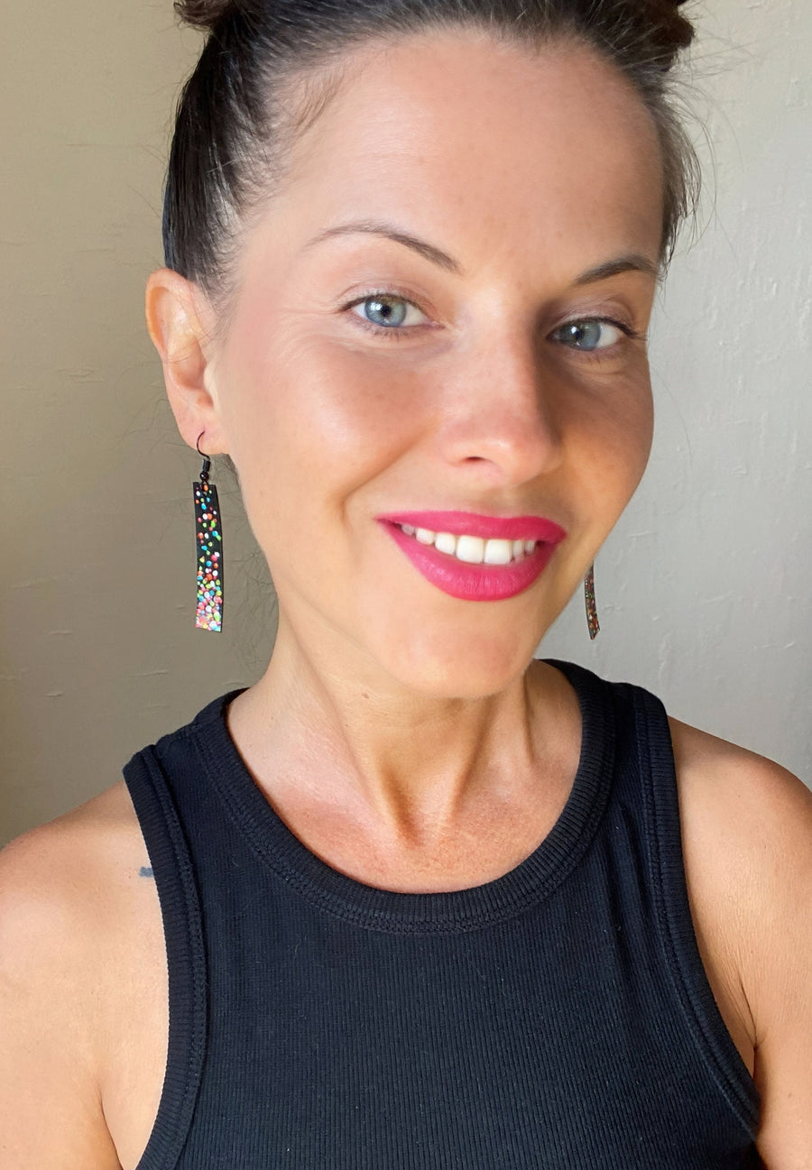 model wears black, upcycled bike inner tube earrings decorated with colourful polka dots