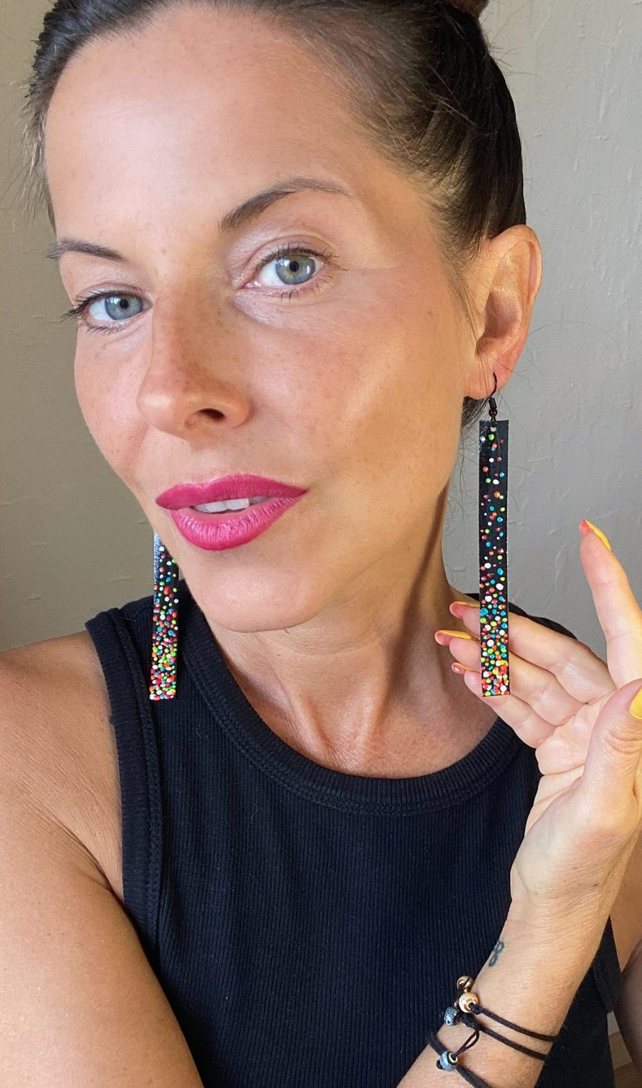 model wears black, upcycled bike inner tube earrings decorated with colourful polka dots