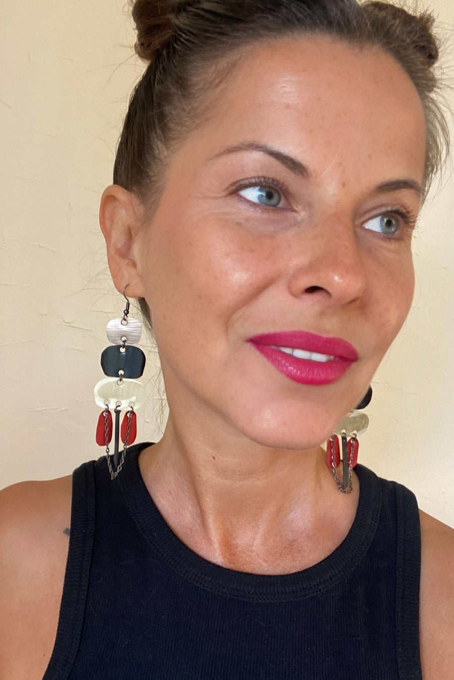 Laura Zabo wears oriental statement earrings made from upcycled Nespresso capsules, apricot, black, sand and red coloured jewelry