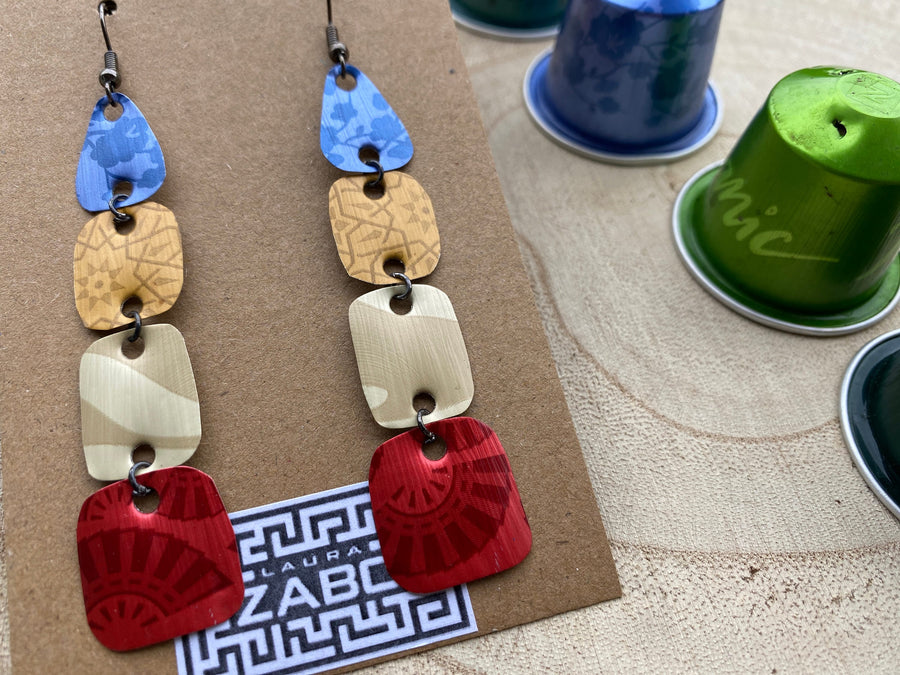 blue brown red, colourful earrings made from upcycled nespresso pods on a wooden background decorated some whole nespresso capsules