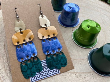 Colourful, Sand, Blue, Green long earrings made from upcycled nespresso capsules on a wooden background with some whole nespresso pods