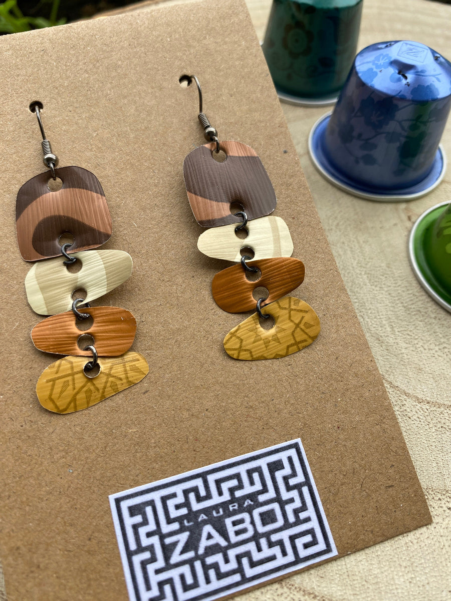 Earthy coloured, brown, sand mustard, gold earrings made from upcycled nespresso capsules on a wooden background with few whole nespresso pods