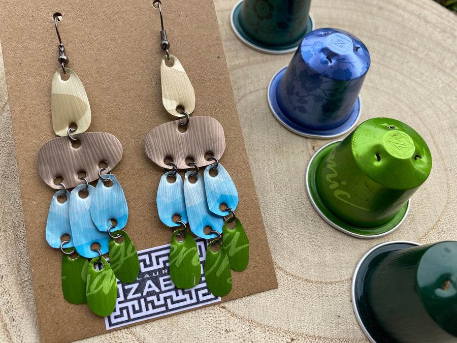 large, long, sand, blue, green earrings made from upcycled nespresso capsules on a wooden background decorated with few nespresso pods