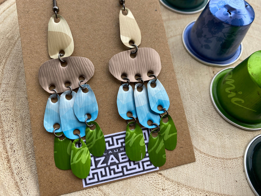 large, long, sand, blue, green earrings made from upcycled nespresso capsules on a wooden background decorated with few nespresso pods