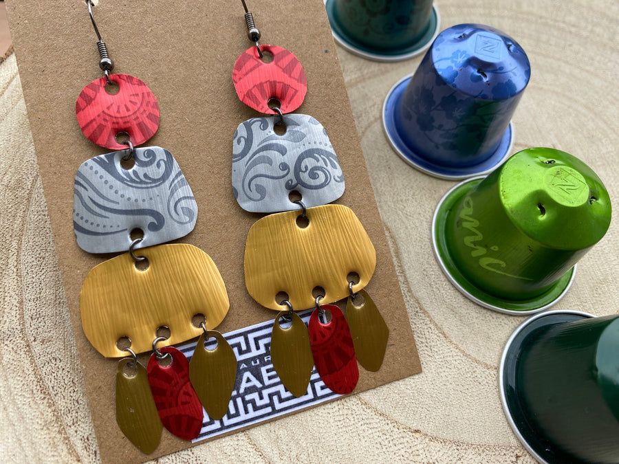 large, long, red, silver, golden earrings made from upcycled nespresso capsules on a wooden background decorated with few nespresso pods