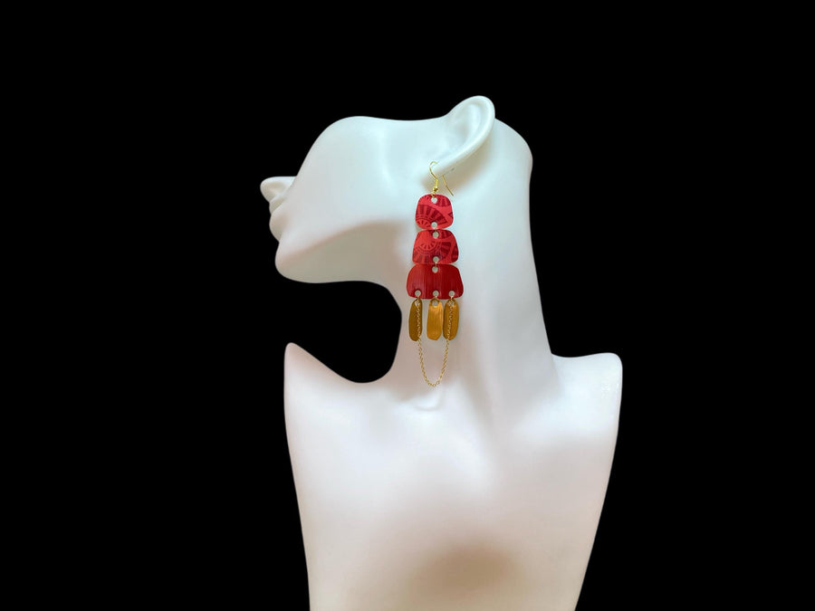 Golden red large earrings made from upcycled nespresso capsules on a white earrings display and black background