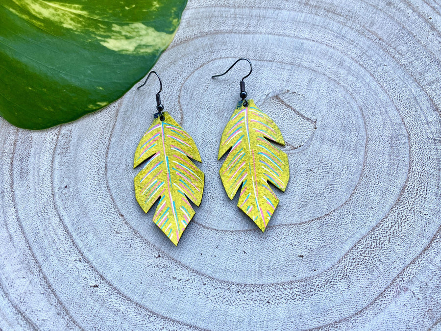 yellow coloured upcycled bicycle inner tube, tyre rubber earrings on a wooden background and a green  leaf