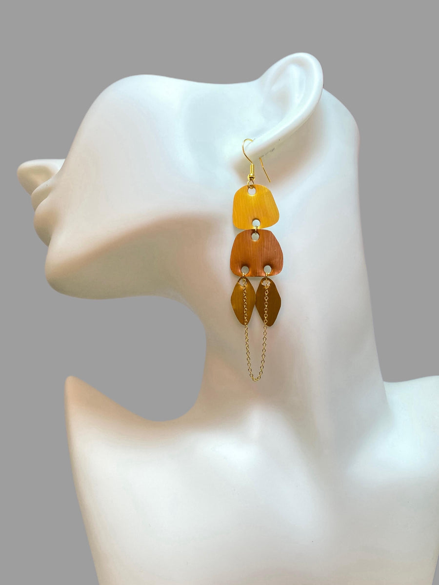 gold, copper, bronze upcycled nespresso capsules earrings on a white mannequin and grey background