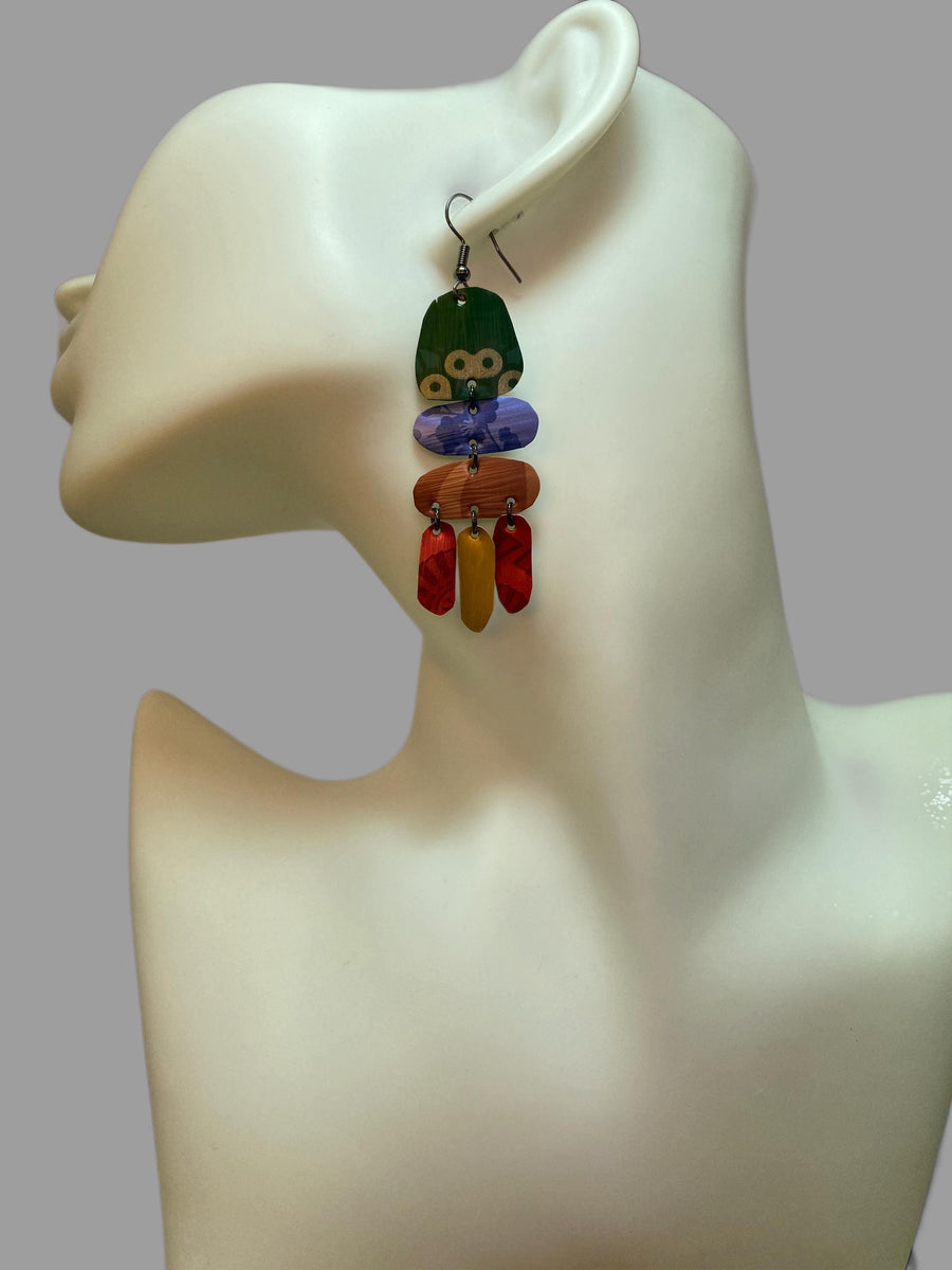 bright, colourful, green, blue, red, gold earrings made from recycled nespresso capsules on a white mannequin and grey background