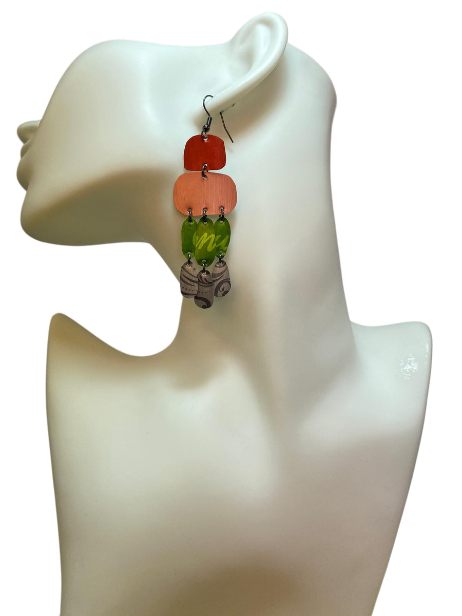 colourful oriental design earrings in red, peach, green and grey colour made from upcycled nespresso capsules on a white mannequin and white background