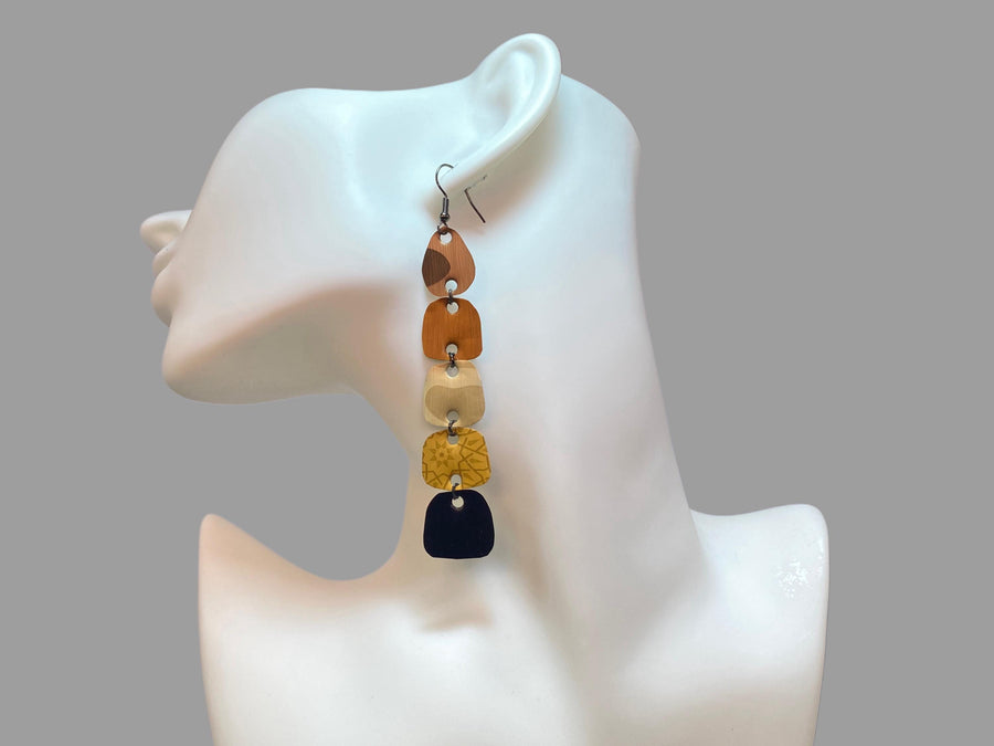 earthy coloured, brown black gold long earrings made from upcycled nespresso capsules on white mannequin and grey background