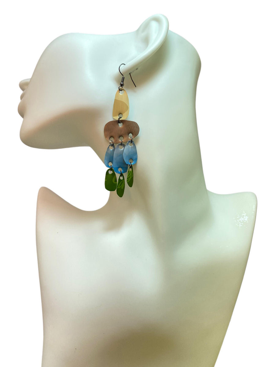 large, long, sand, blue, green earrings made from upcycled nespresso capsules on a white mannequin and white background