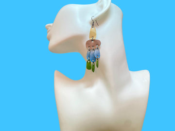 large, long, sand, blue, green earrings made from upcycled nespresso capsules on a white mannequin and blue background