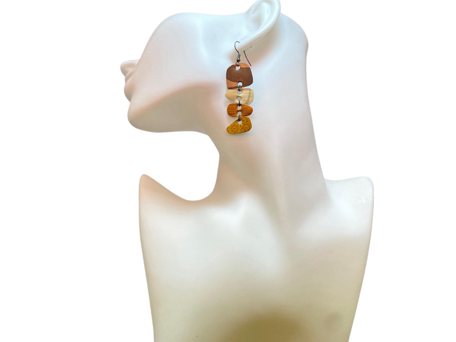 Earthy coloured, brown, sand mustard, gold earrings made from upcycled nespresso capsules on a white mannequin and white background