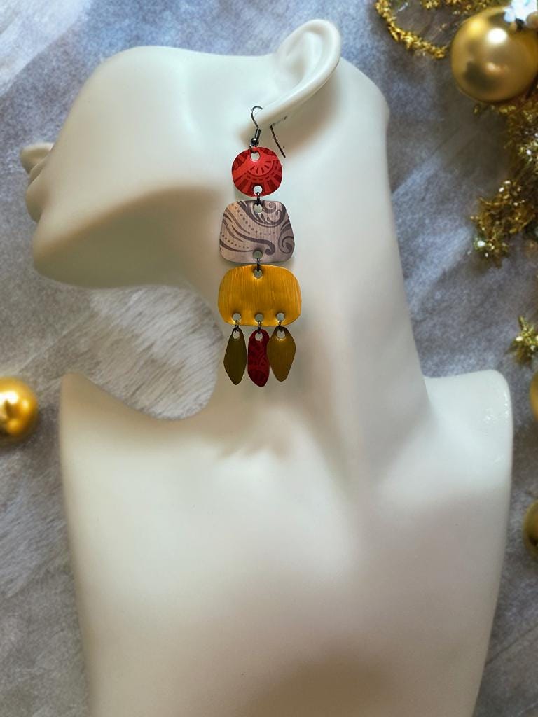 large, long, red, silver, golden earrings made from upcycled nespresso capsules on a white mannequin and xmas themed background