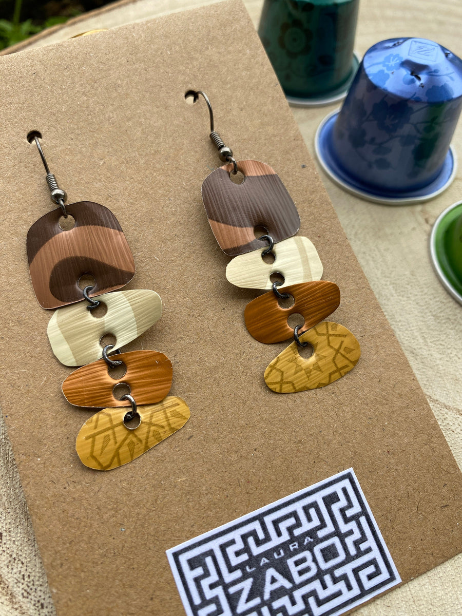 Earthy coloured, brown, sand mustard, gold earrings made from upcycled nespresso capsules on a wooden background with few whole nespresso pods