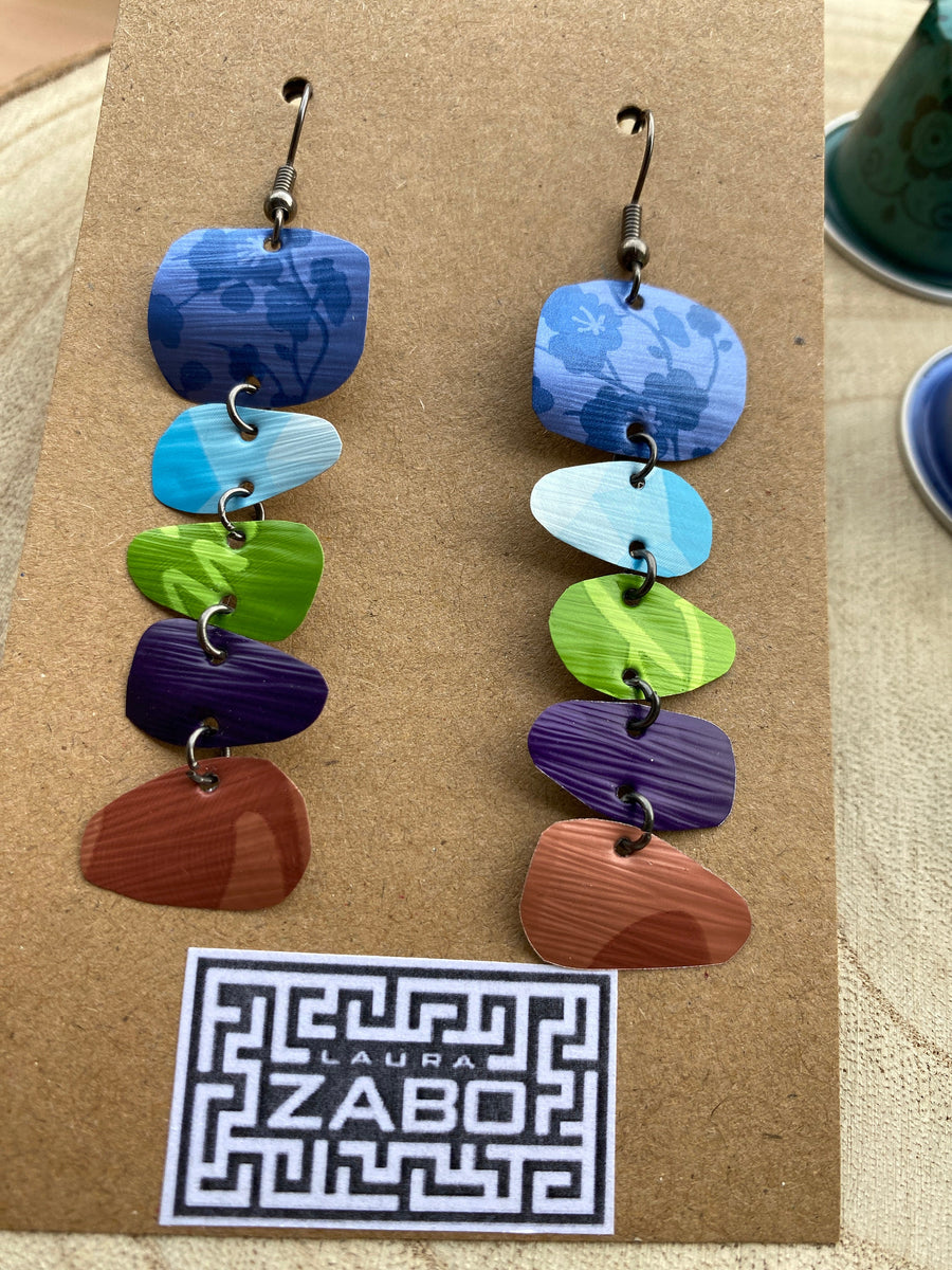 zen, yoga inspired colourful earrings made from upcycled nespresso capsules on a wooden background with few nespresso pods and Laura Zabo logo